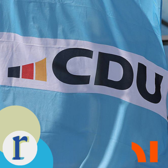 A close-up of a light-blue flag bearing the logo of the CDU (Christian Democratic Union), a German political party.