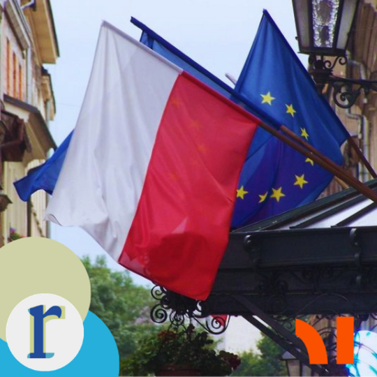 The Polish flag and the EU flag flying together from a building facade on a European old-town street, with a wrought-iron lamp and balconies visible.