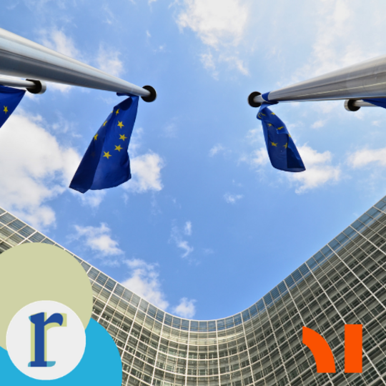 A low-angle shot looking straight up at two EU flags on poles, against a blue sky, with a curved glass building visible below.