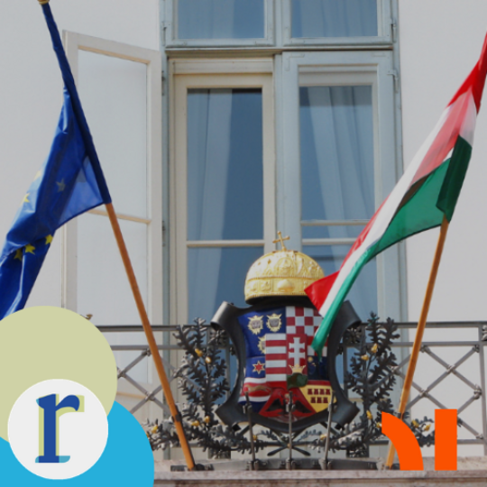 Hungary's coat of arms, topped with the Holy Crown, mounted on a balcony railing between the EU flag and the Hungarian flag.