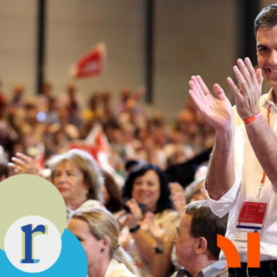 A man in a yellow shirt applauding before a large indoor crowd waving red flags, at what appears to be a Spanish political party rally — the man's likeness resembles Prime Minister Pedro Sánchez, though I can't be certain from the image alone.