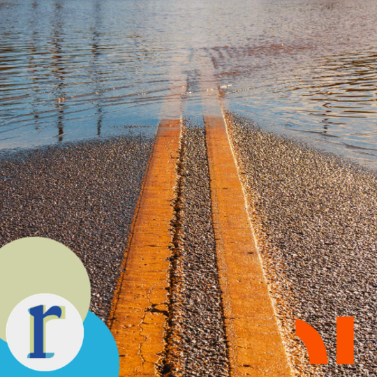 A wooden boardwalk running into calm floodwater, its far end submerged and reflected on the water's surface