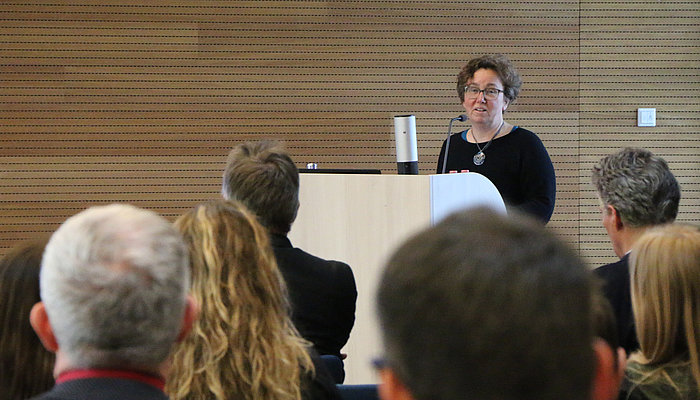Speaker at a podium with audience visible.