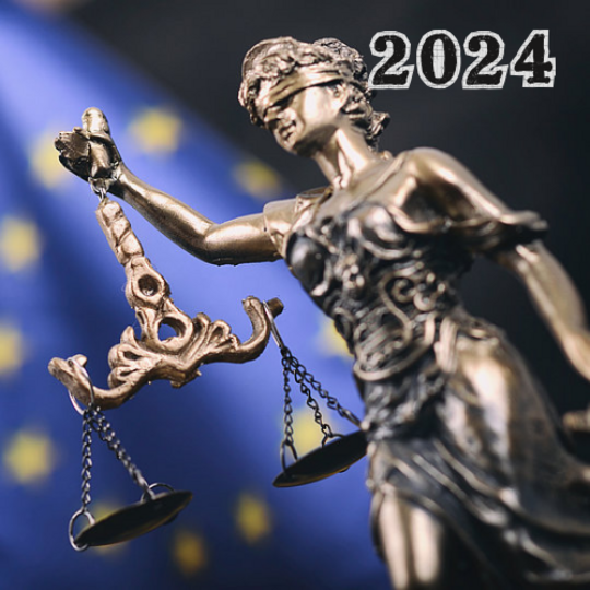 A bronze statue of a blindfolded Lady Justice holding a set of scales, against a blue backdrop scattered with gold stars, next to the bold text "2023".