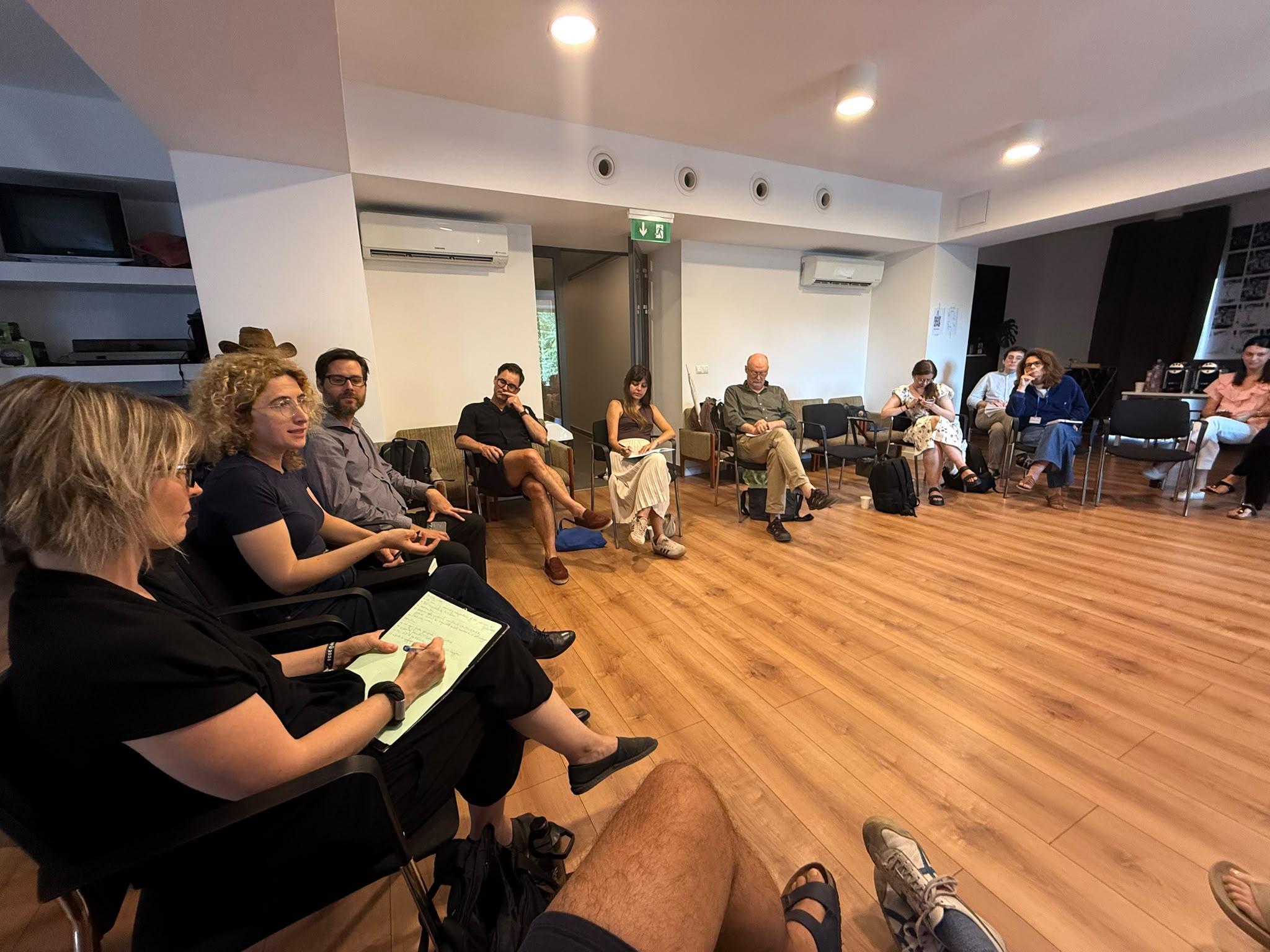 Summer university participants sit in circle in a seminar room during a panel discussion, engaged in the group discussion.